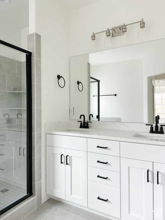 Full bath with a shower stall, double vanity, and tile patterned flooring