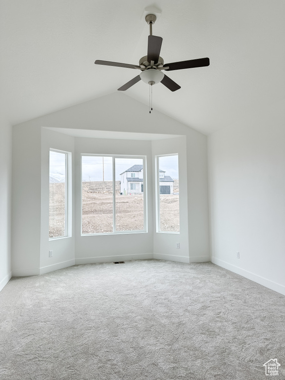Spare room featuring vaulted ceiling, carpet flooring, and ceiling fan