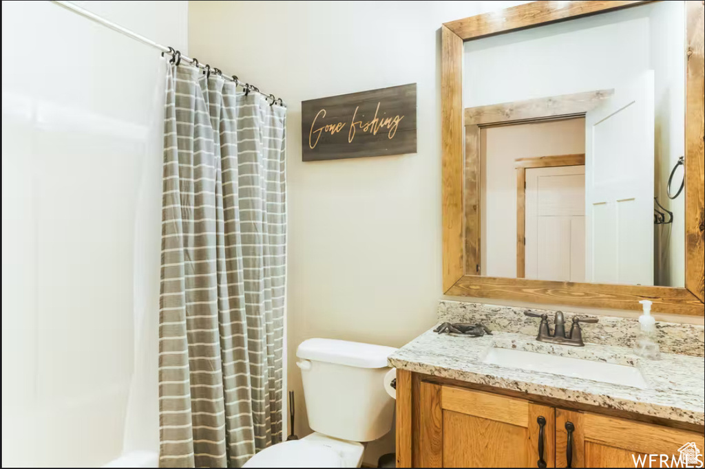 Bathroom featuring toilet, a shower with shower curtain, and vanity