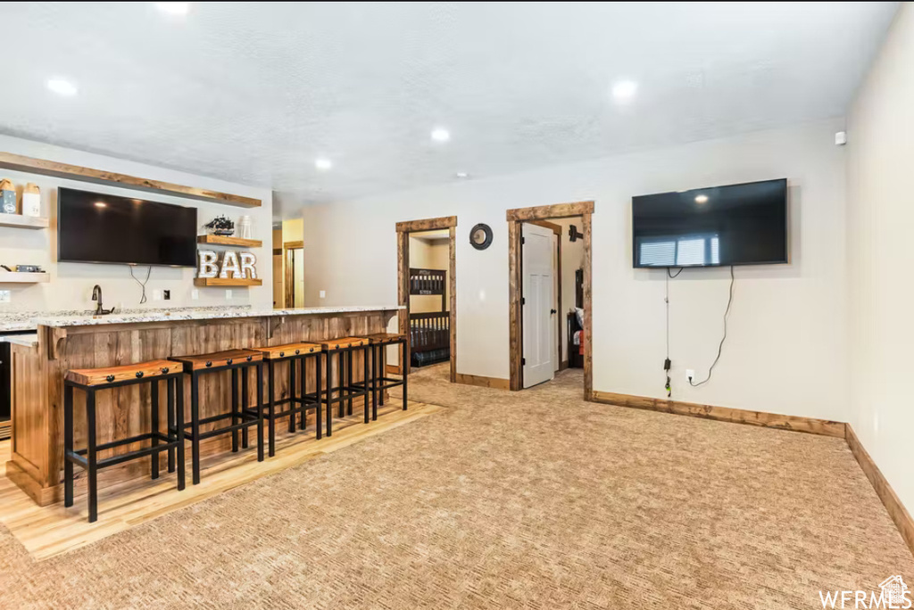 Bar with wet bar, recessed lighting, light carpet, a sink, and baseboards