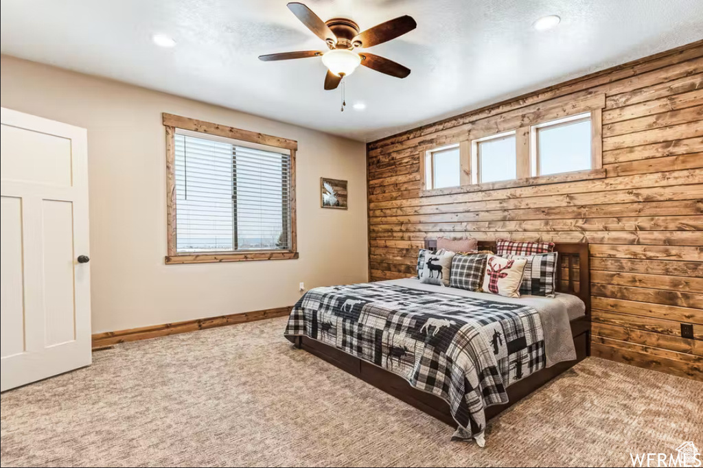 Carpeted bedroom with wooden walls, baseboards, recessed lighting, and ceiling fan