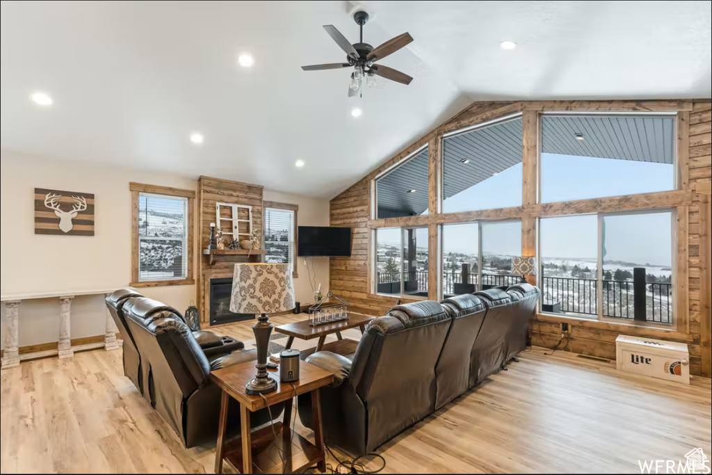 Living room with high vaulted ceiling, light wood-type flooring, plenty of natural light, and a ceiling fan