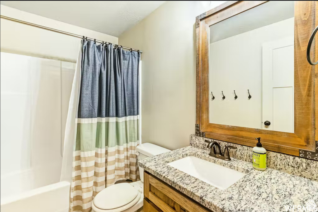 Full bathroom with toilet, shower / bath combo with shower curtain, and vanity