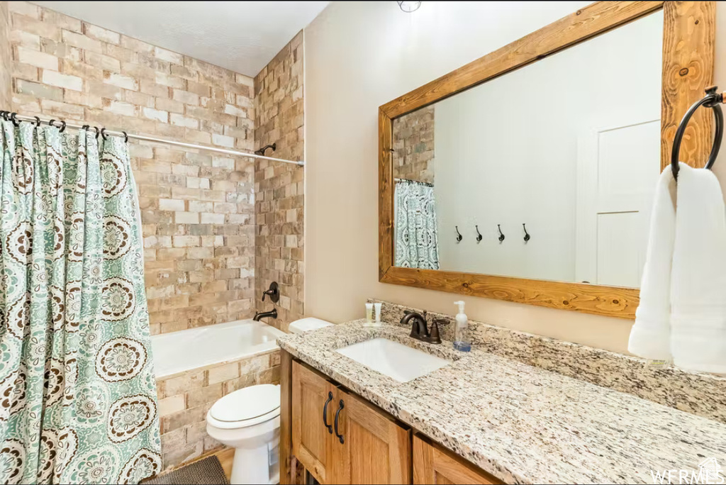 Bathroom featuring shower / bathtub combination with curtain, vanity, and toilet