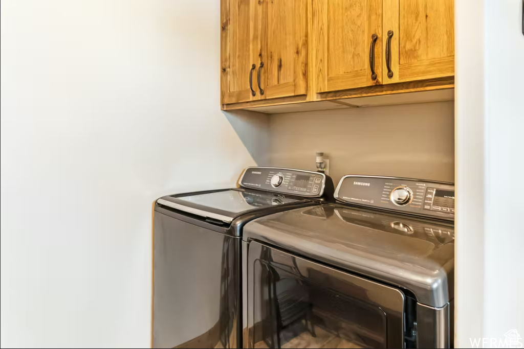 Clothes washing area featuring independent washer and dryer and cabinet space