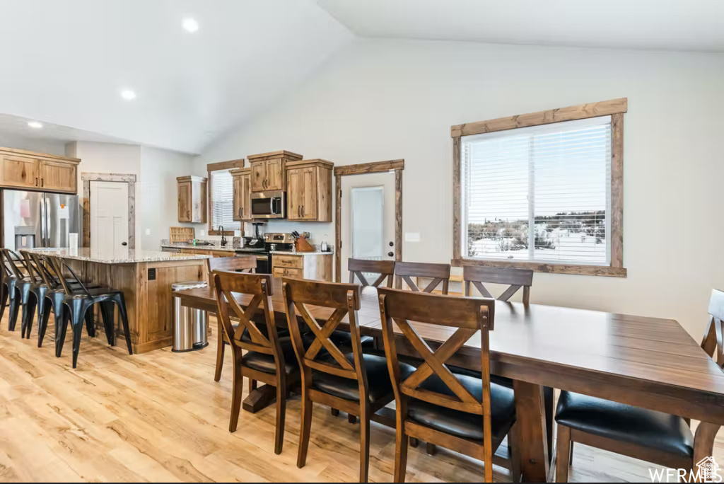 Dining room featuring high vaulted ceiling, light wood-type flooring, and recessed lighting