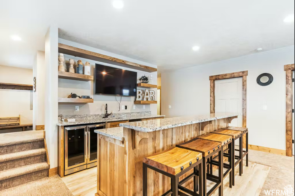 Bar featuring baseboards, wet bar, recessed lighting, light wood finished floors, and beverage cooler