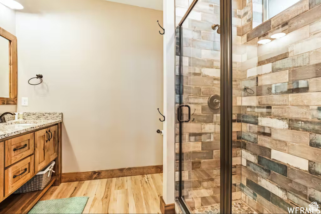 Bathroom with a shower stall, vanity, baseboards, and wood finished floors