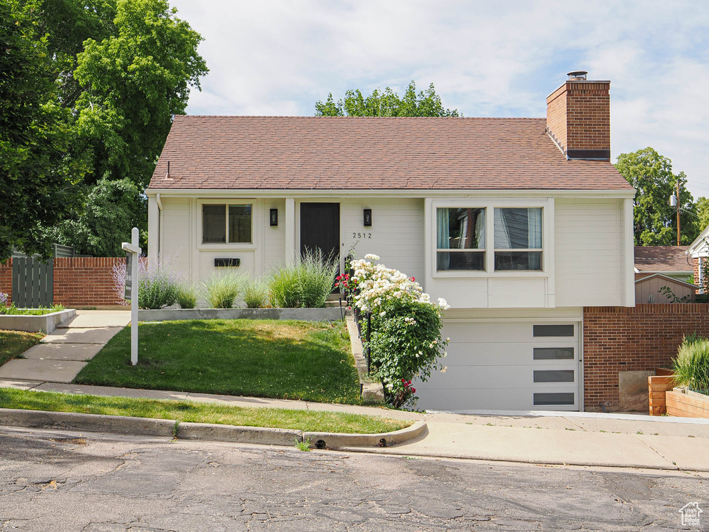 View of front of home featuring a chimney, a garage, and driveway