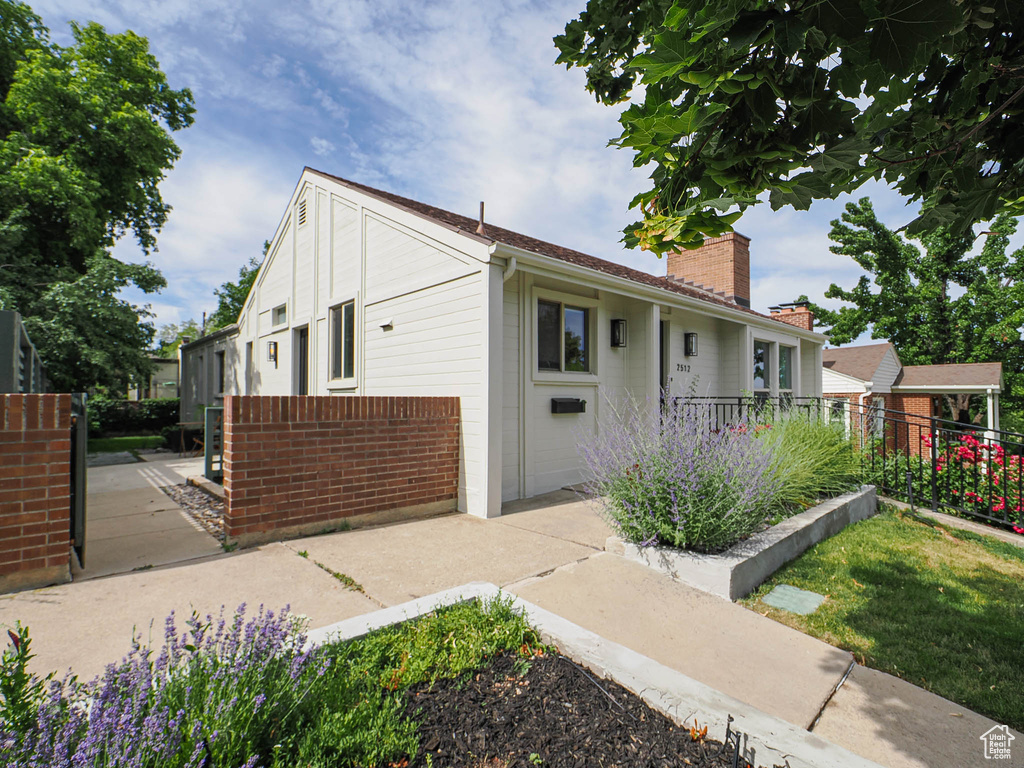 View of front of property featuring a chimney and brick siding
