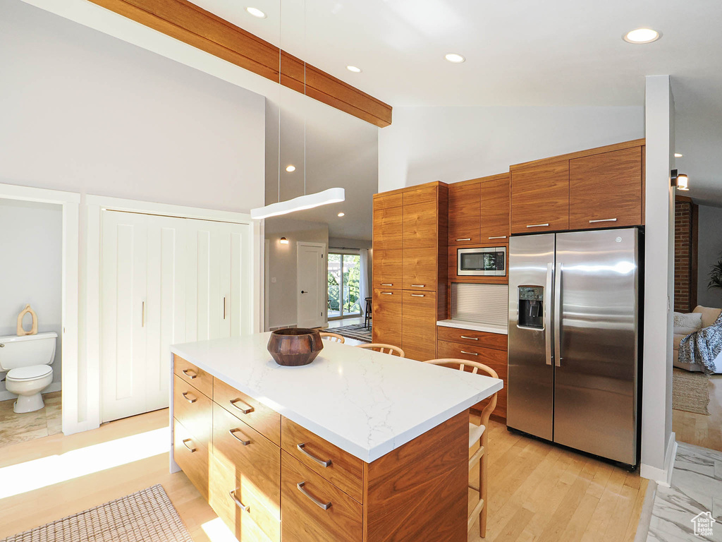 Kitchen featuring appliances with stainless steel finishes, brown cabinets, a center island, modern cabinets, and high vaulted ceiling