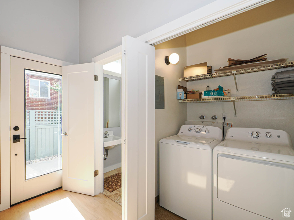 Laundry area with washing machine and dryer, light wood-style floors, and electric panel