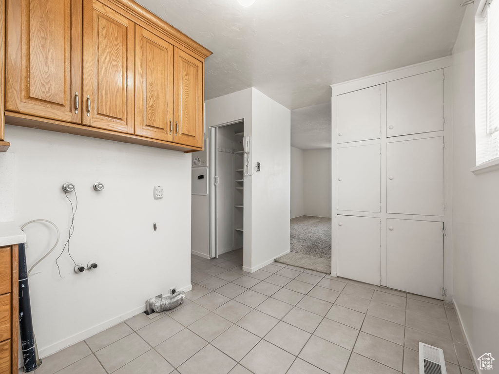 Laundry room featuring cabinet space, light tile patterned flooring, hookup for a washing machine, and hookup for an electric dryer