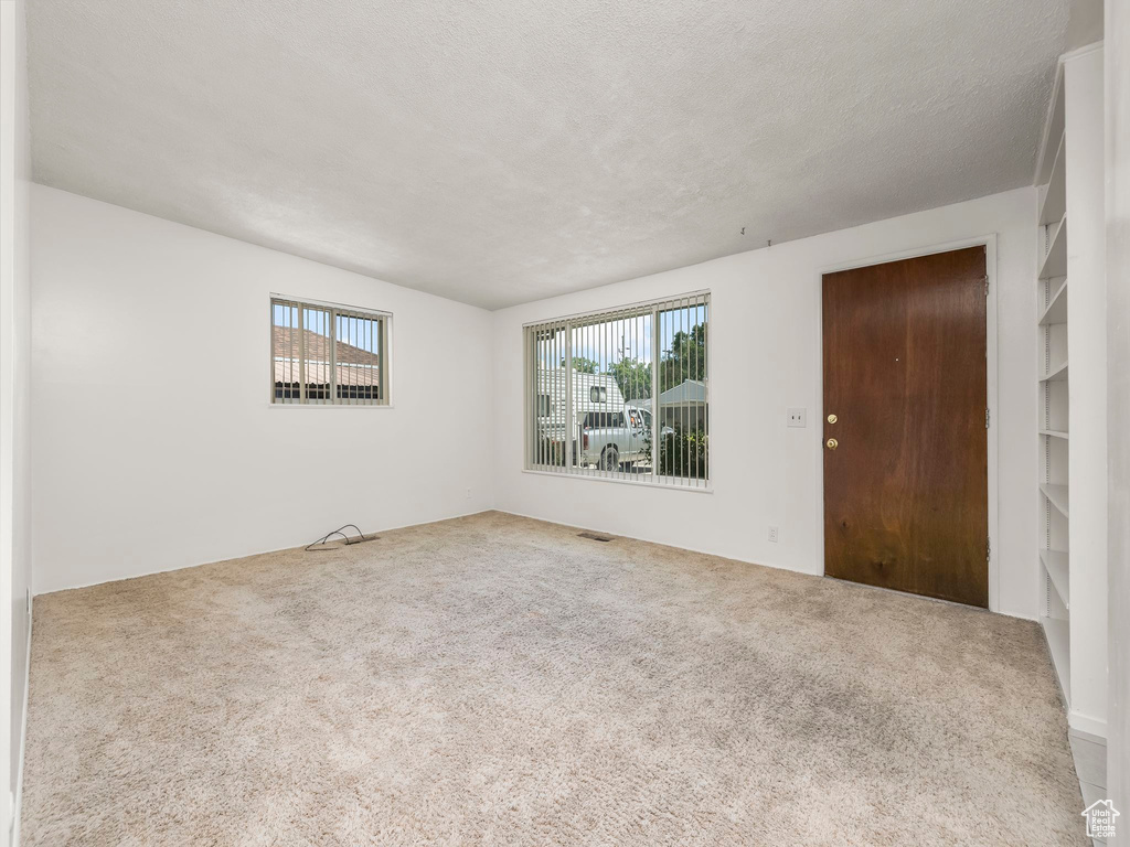 Carpeted spare room featuring a textured ceiling
