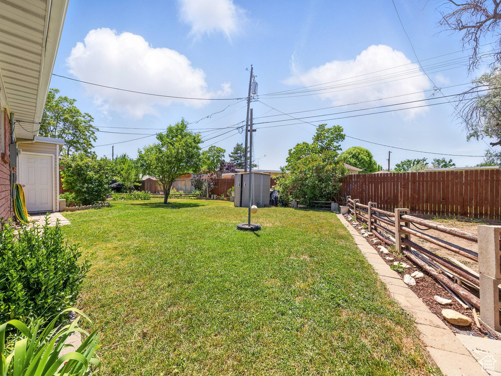 Fenced backyard featuring a storage shed