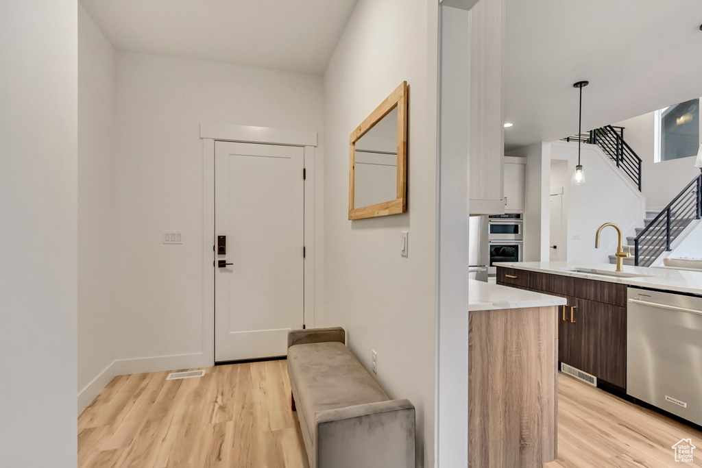 Kitchen featuring stainless steel appliances, light wood-style flooring, light countertops, and hanging light fixtures