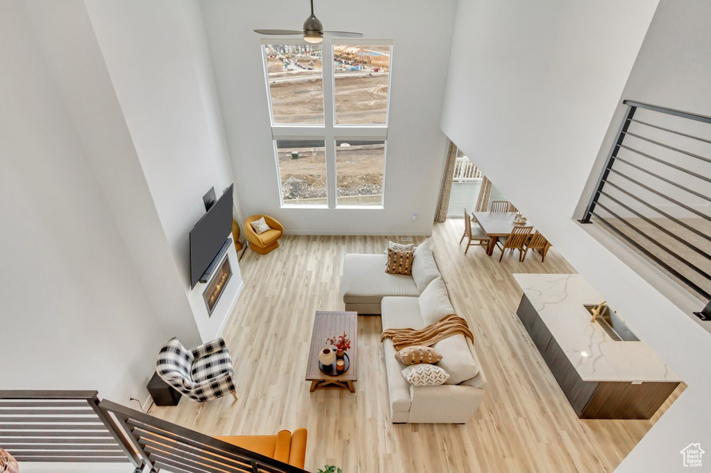 Living area with wood finished floors, ceiling fan, and a towering ceiling