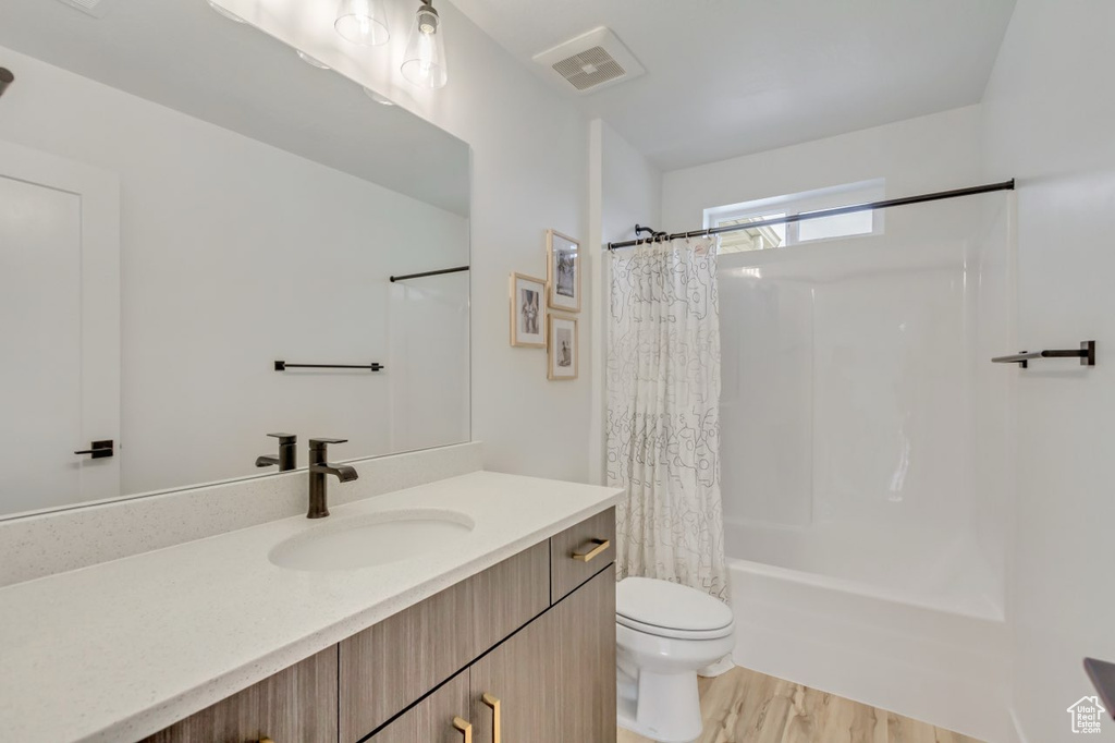 Full bathroom with vanity, shower / bath combo, and wood finished floors