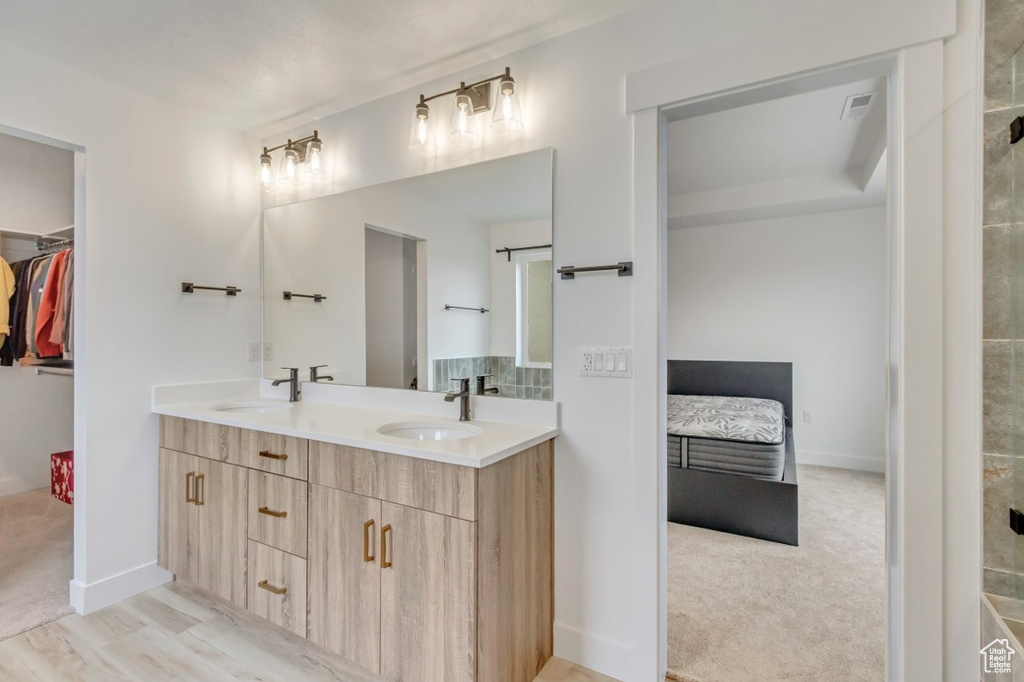 Bathroom featuring double vanity, ensuite bath, and a walk in closet