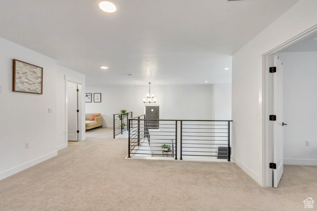 Hall with light carpet, an upstairs landing, recessed lighting, and a chandelier