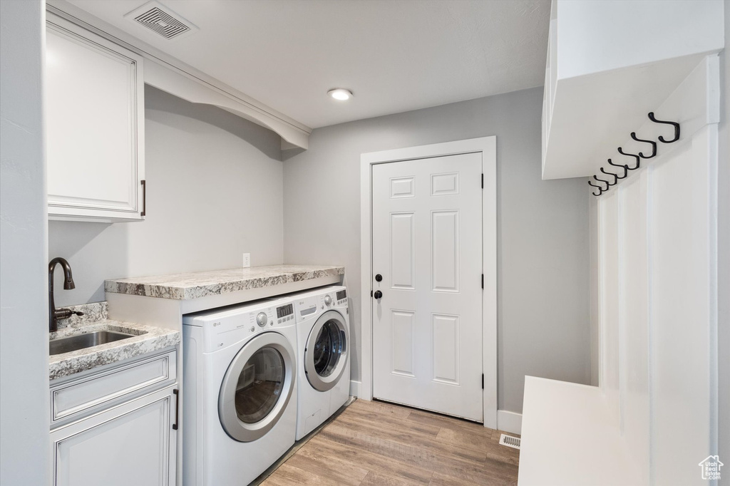 Laundry room featuring washer and dryer, cabinet space, light wood-type flooring, and recessed lighting