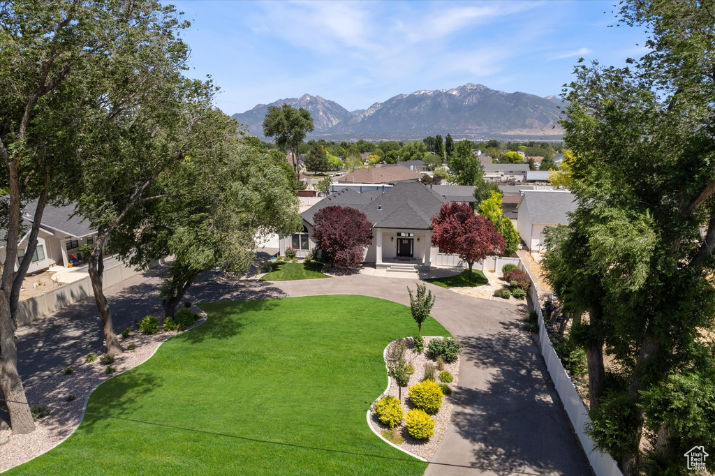 View of front of home with a mountain view, curved driveway, a front yard, stucco siding, and a residential view