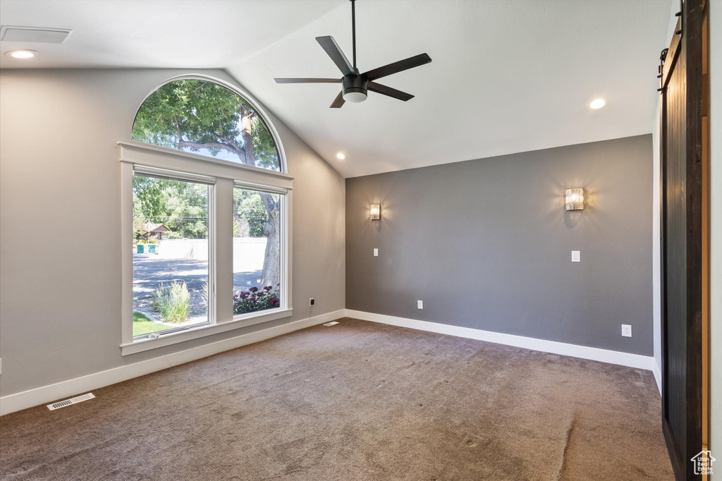 Carpeted empty room with a barn door, vaulted ceiling, ceiling fan, and recessed lighting