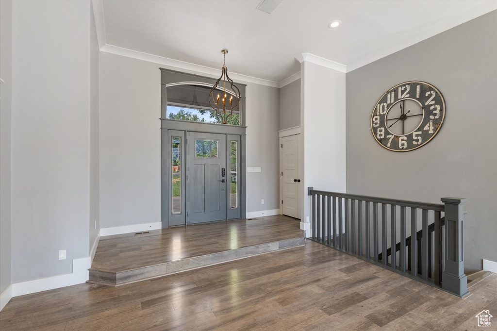 Foyer entrance featuring ornamental molding, wood finished floors, a chandelier, and recessed lighting