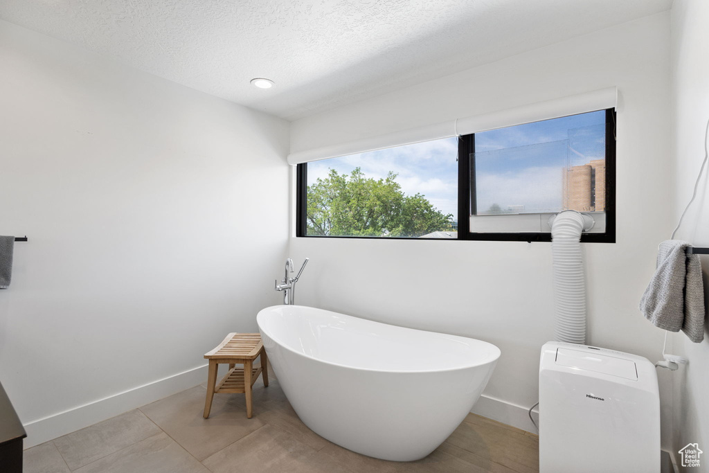 Bathroom with a freestanding bath and a textured ceiling