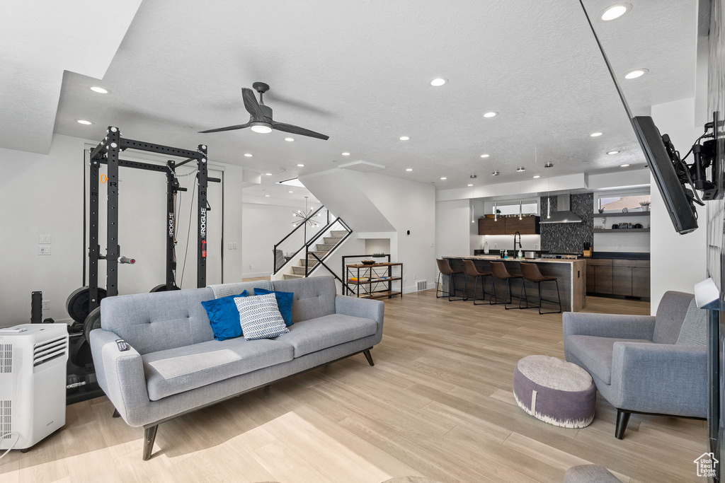 Living room with recessed lighting, light wood finished floors, stairs, and a ceiling fan