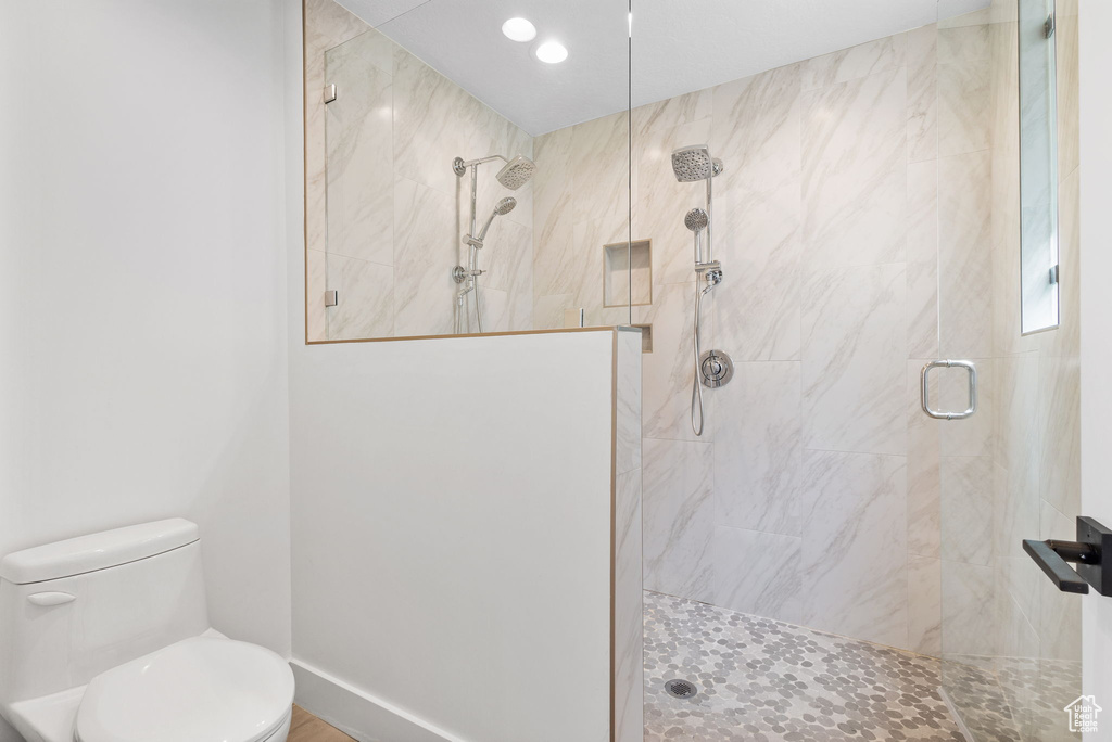 Full bath featuring tiled shower and toilet