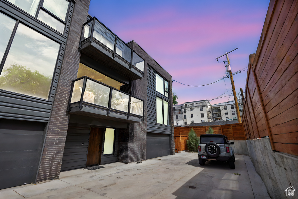 Property exterior at dusk with brick siding, an attached garage, and concrete driveway