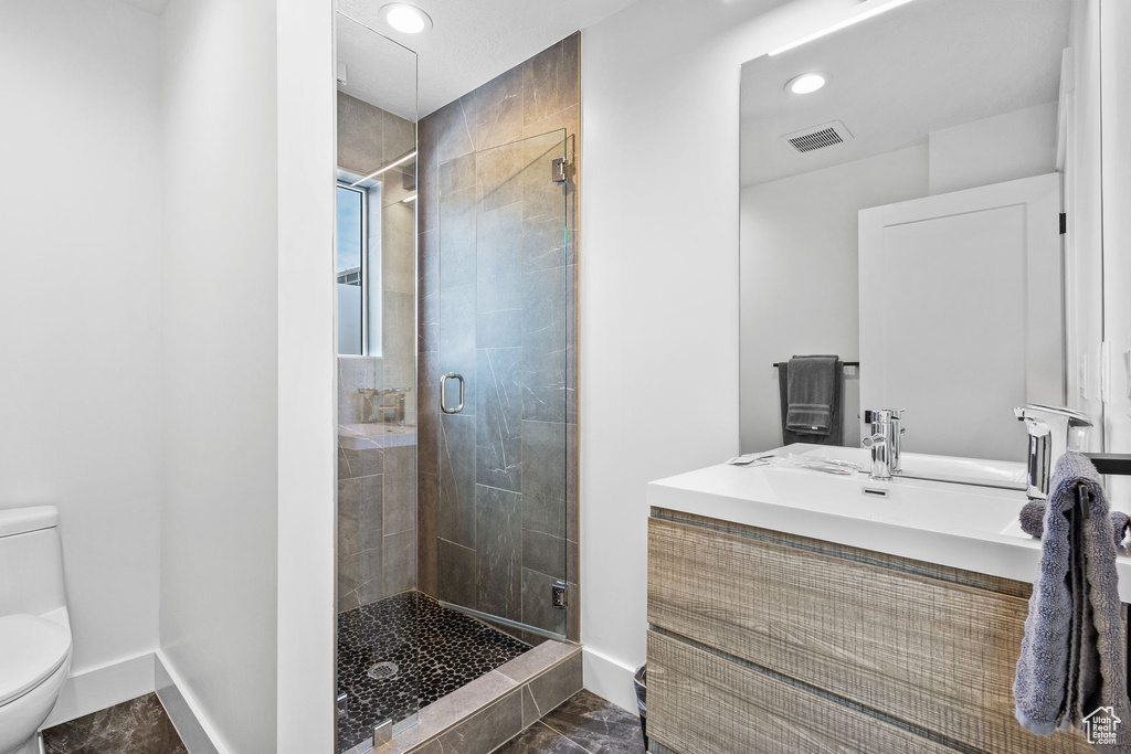 Bathroom with a shower stall, vanity, and recessed lighting