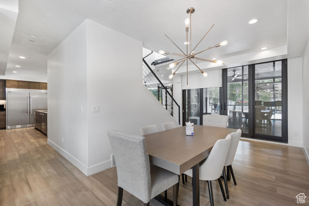 Dining room with stairs, light wood finished floors, a chandelier, and recessed lighting