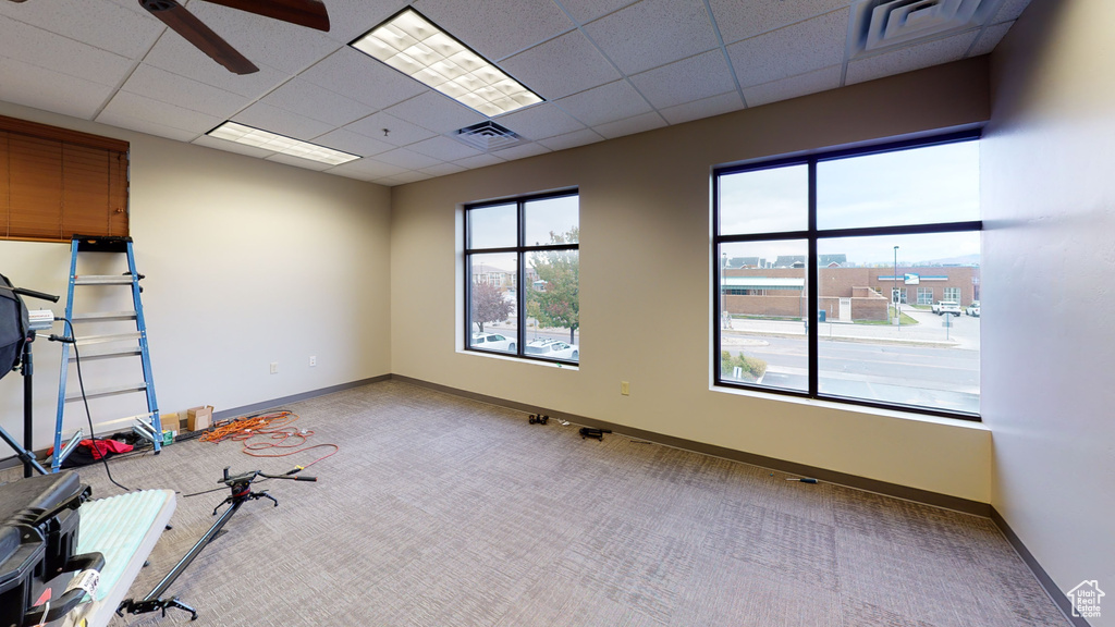 Empty room featuring carpet, a ceiling fan, and a paneled ceiling