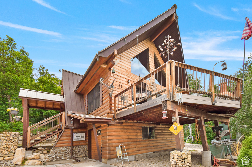 View of home\\\'s exterior featuring stairs, a metal roof, and a wooden deck