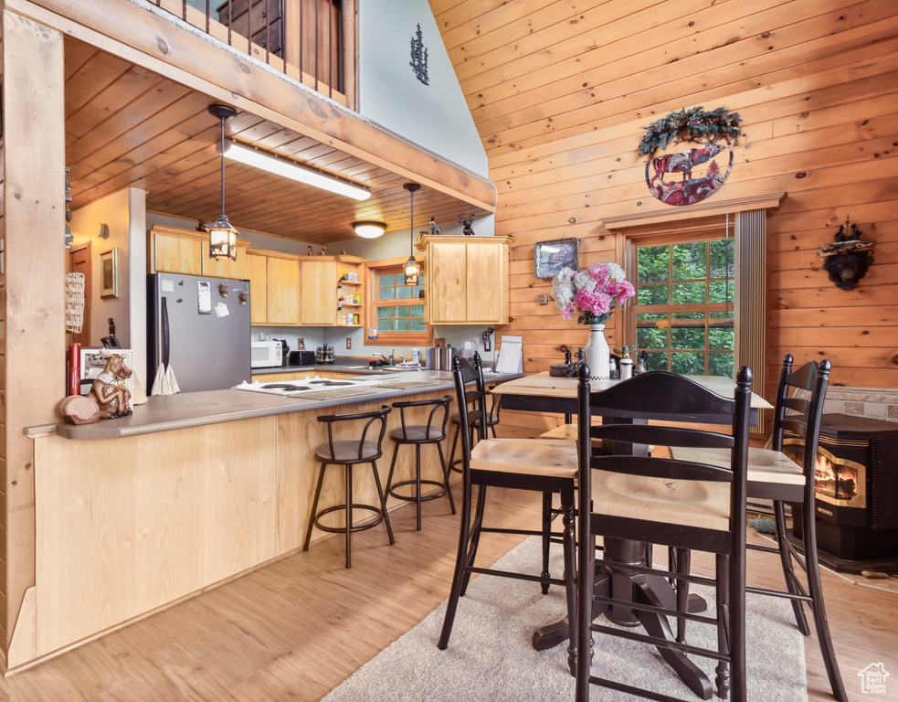 Dining room with light wood-type flooring, wood walls, high vaulted ceiling, and wood ceiling