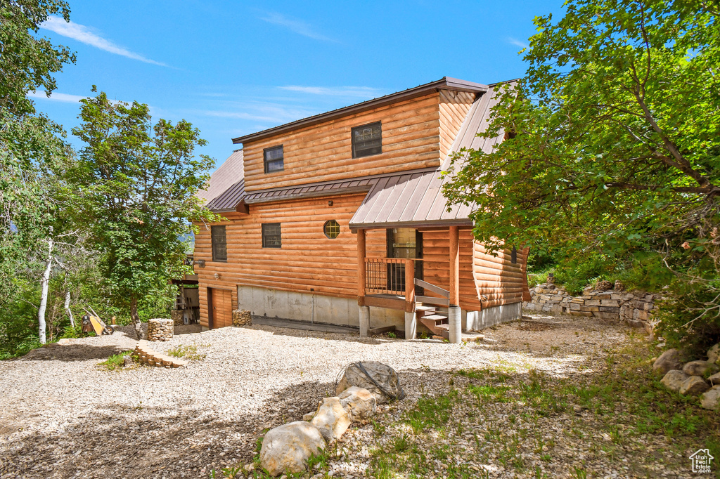 Rear view of property featuring log veneer siding and a metal roof