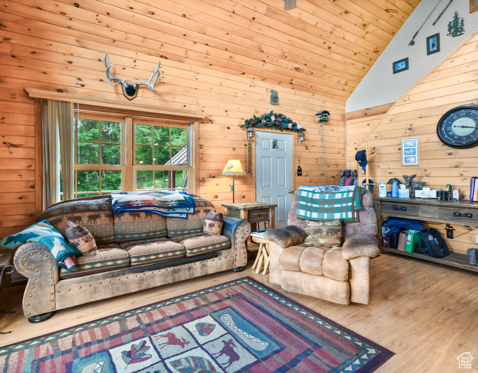 Living area with wood walls, wood finished floors, and lofted ceiling