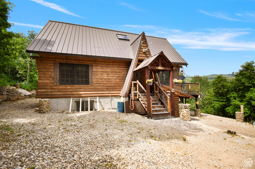 View of front of house featuring a metal roof, a wooden deck, and stairs