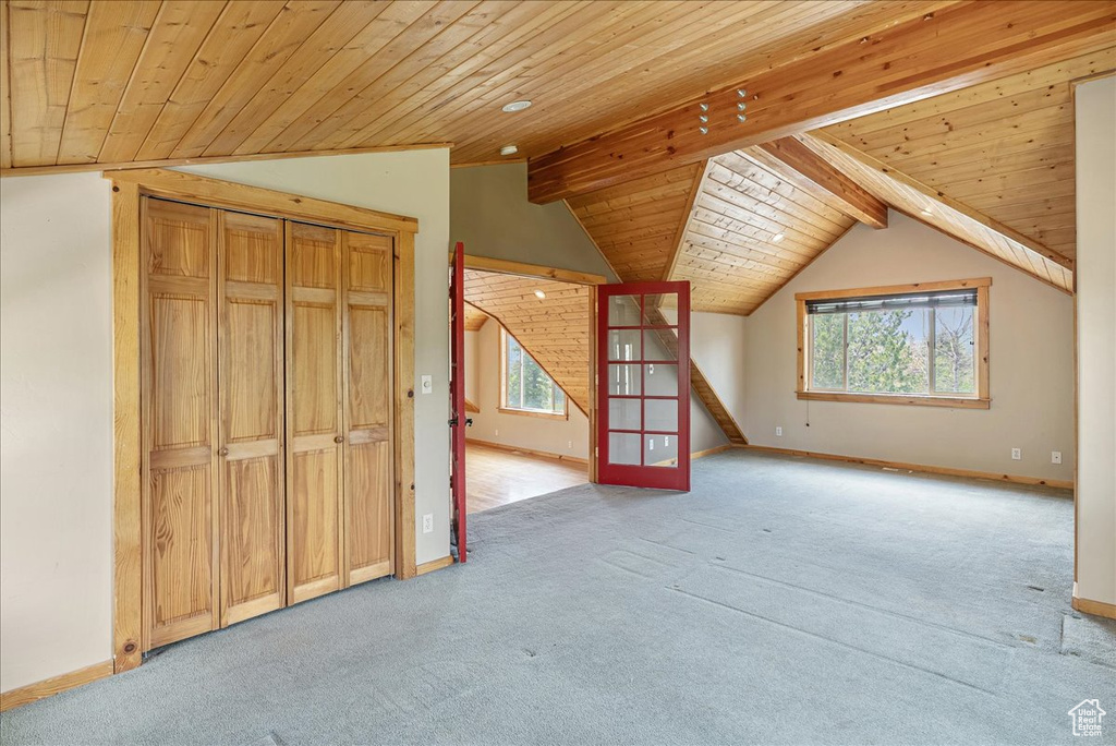 Unfurnished living room featuring carpet flooring, wood ceiling, and lofted ceiling