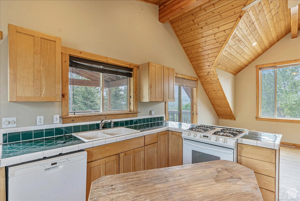Kitchen featuring white appliances, light brown cabinetry, wood ceiling, a peninsula, and tile counters