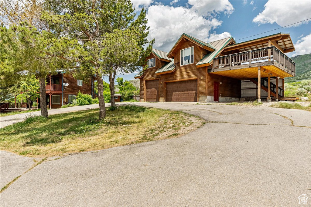 View of front facade featuring driveway, a garage, a metal roof, and stairs