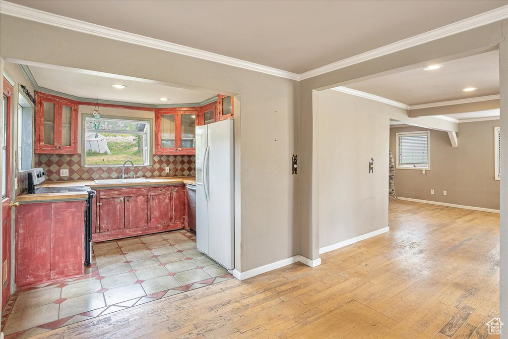 Kitchen featuring white fridge with ice dispenser, light wood-style flooring, crown molding, tasteful backsplash, and range with electric stovetop