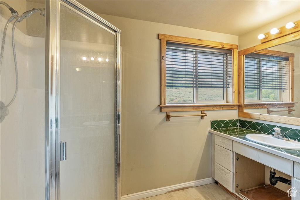 Full bathroom with a shower stall, vanity, and backsplash