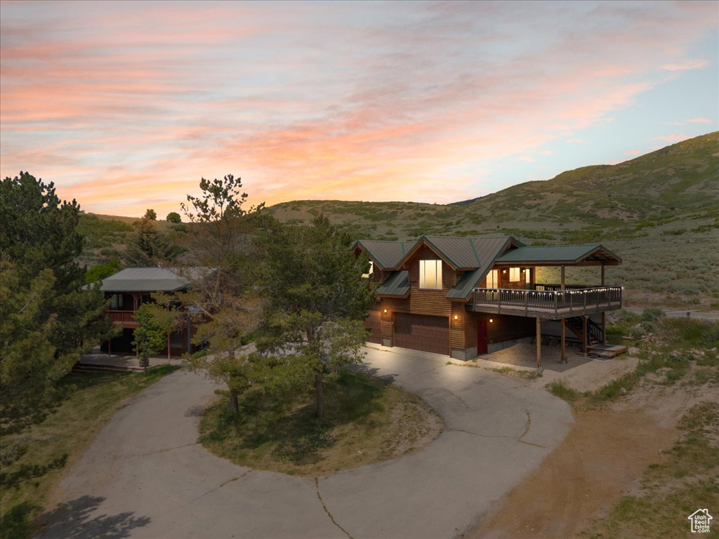 View of front of house featuring curved driveway, a deck with mountain view, and a metal roof