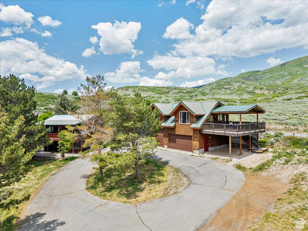 View of front of home featuring curved driveway, an attached garage, a deck with mountain view, a metal roof, and stairs