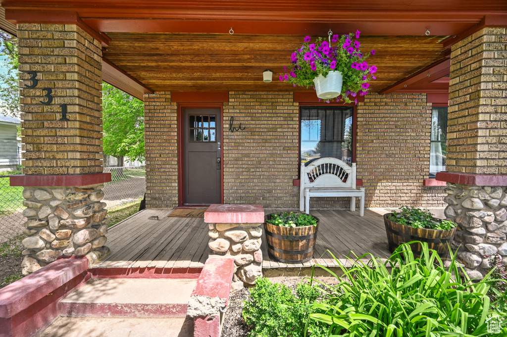 Doorway to property with a porch and brick siding