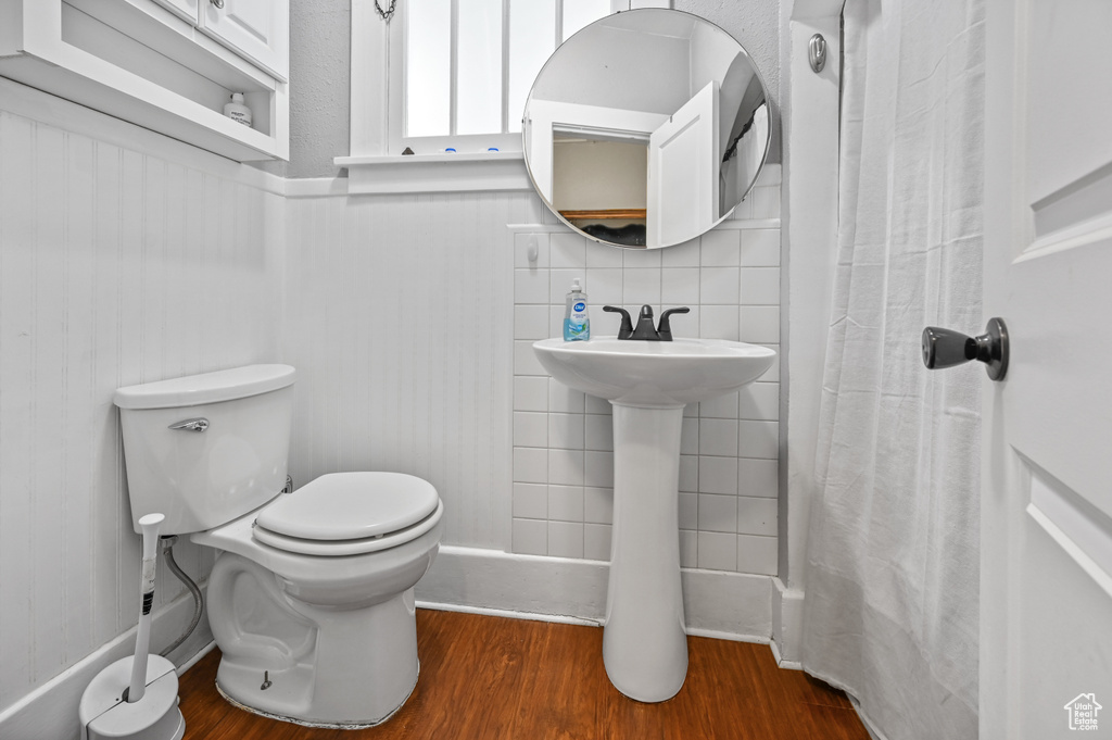 Bathroom with wood finished floors, wainscoting, and a shower with shower curtain