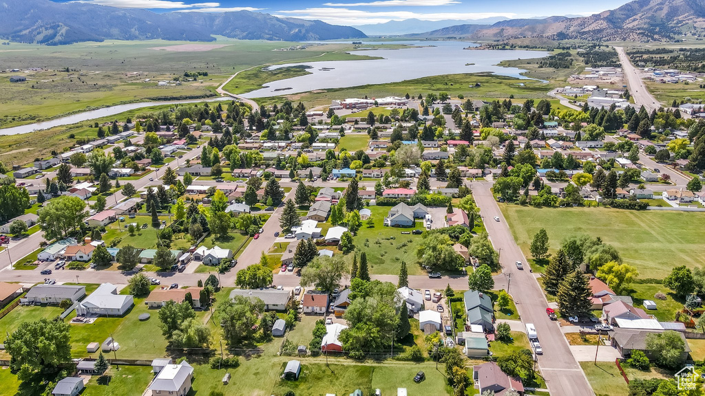 Aerial view of property and surrounding area with a water and mountain view and nearby suburban area